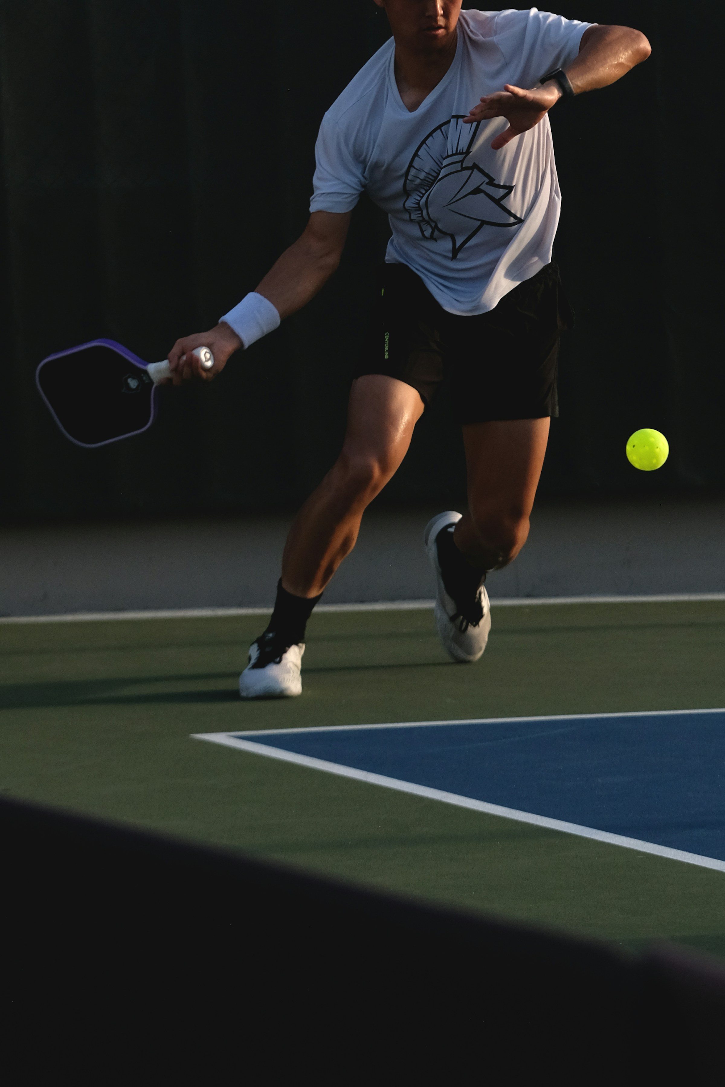 Pickleball player reaching for a shot on court